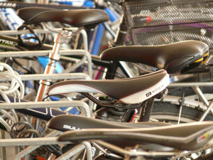Close-up of different bike saddles on a row of bicycles