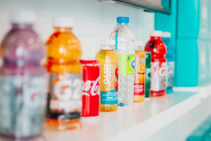 Row of colorful, sugary sports drinks and sodas lined up against a wall