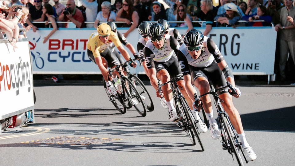 Peloton of cyclists riding hard around a turn in a race in London