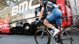 Cyclist riding bicycle passing BMC bus at daytime