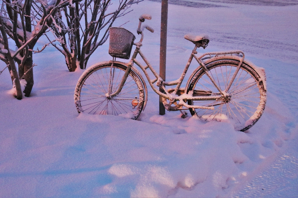 Commuter bicycle covered in snow and leaning on a lamppost