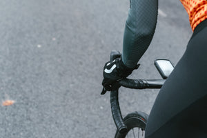 Side of a cyclist's hand with smiley-face glove, gripping the hoods of their handlebars as they pedal