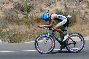 Man pedaling hard on a cycling time trial on a desert road