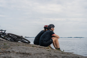 Man and woman taking a break from cycling to sit on a riverbank