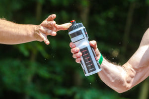 Close-up of two cyclists’ hands passing a water bottle between them