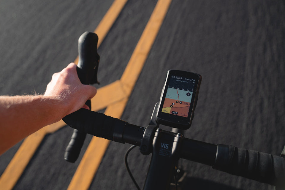 Looking down from a cyclist’s point of view at a GPS cycling computer mounted on the handlebars of a road bike