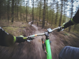 A mountain biker’s view of the trail and cycling GPS while riding through the woods