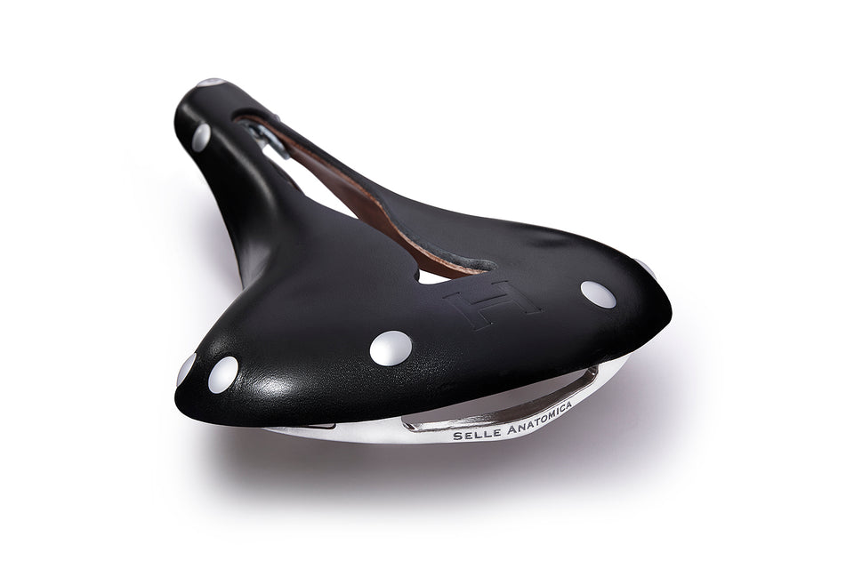 The H2 leather bicycle saddle in black with silver rivets, showing off the Selle Anatomica logo carved into the back of the stainless series 2 frame